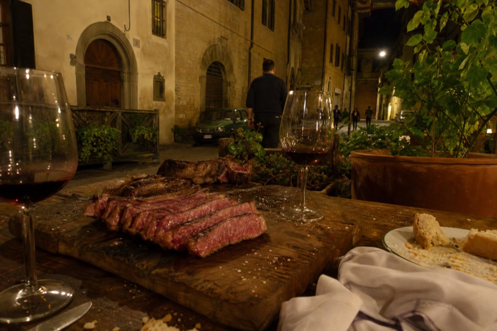 Sliced steak and glasses of red wine arranged on a rustic restaurant table