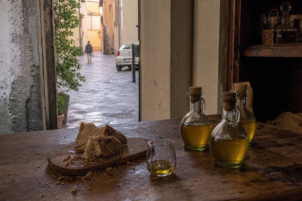 Bottles of golden olive oil and bread on a wooden tasting counter