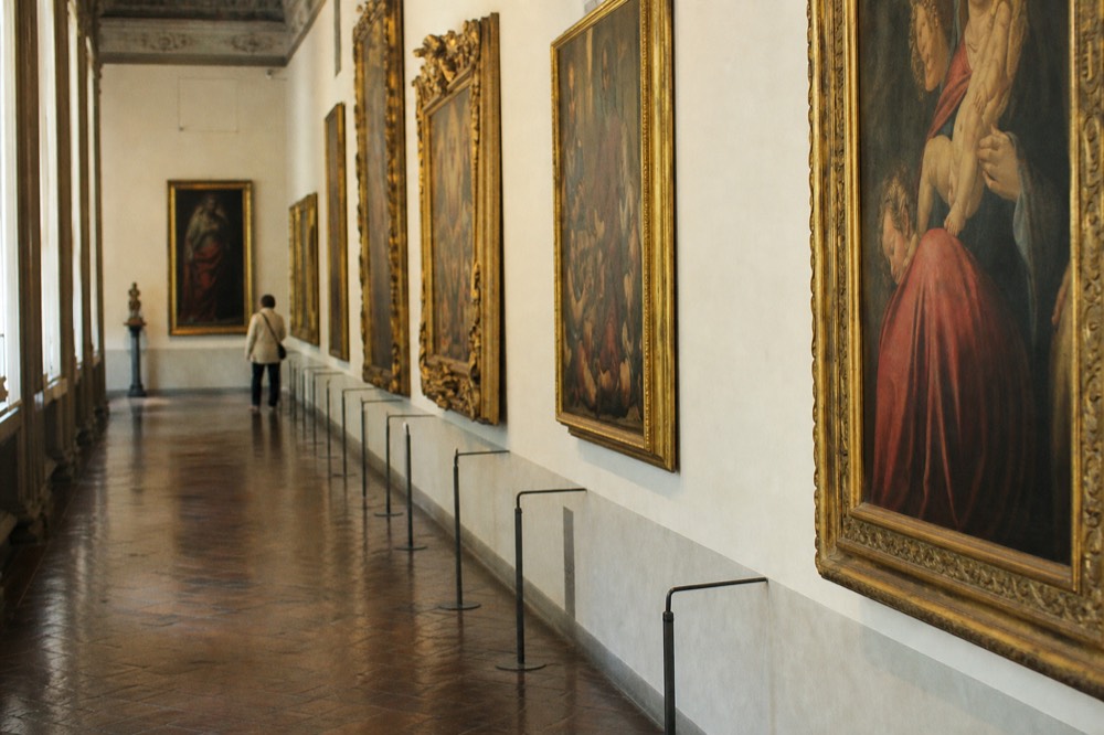 Gallery corridor with Renaissance paintings hung frame to frame along a long hall
