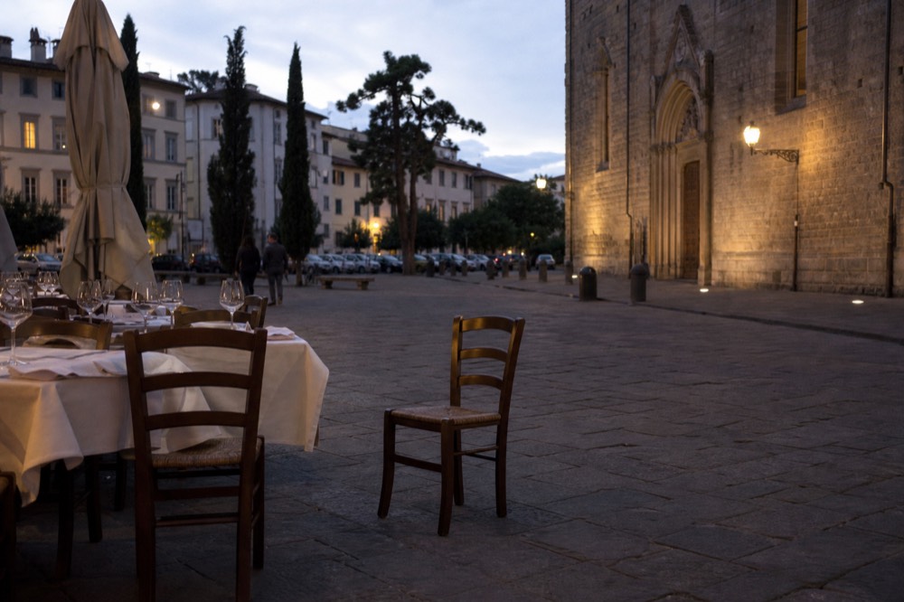 Tables set with wine glasses on a stone street in the evening