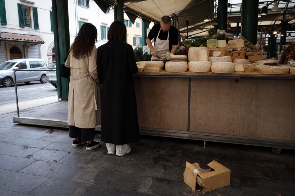 Chef and small group at a market stall selecting cheese and produce