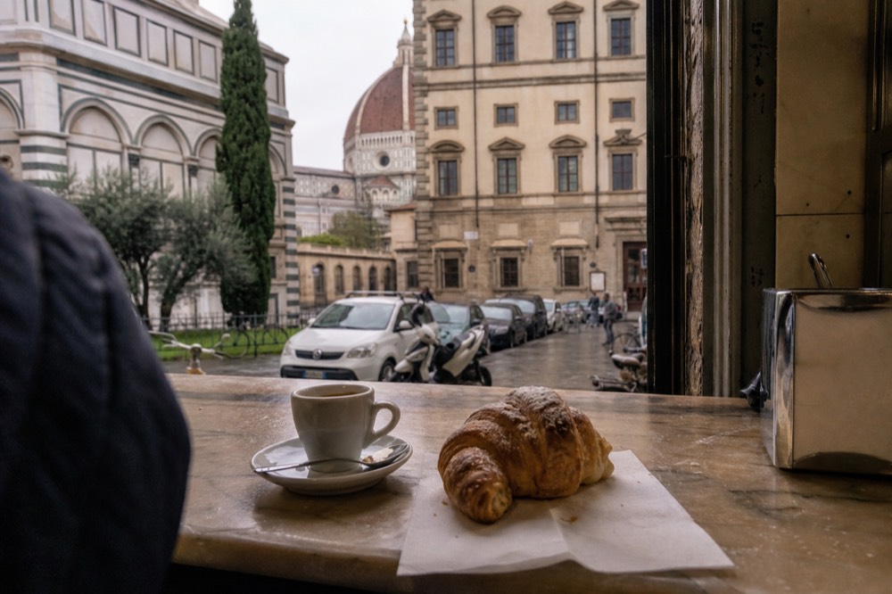 Espresso cup and cornetto on a marble bar counter in a Florence cafe