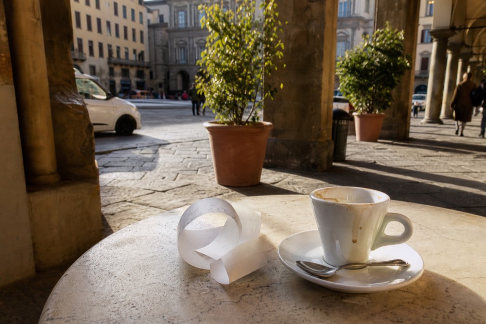 A paper receipt resting on a marble café counter beside an empty espresso cup