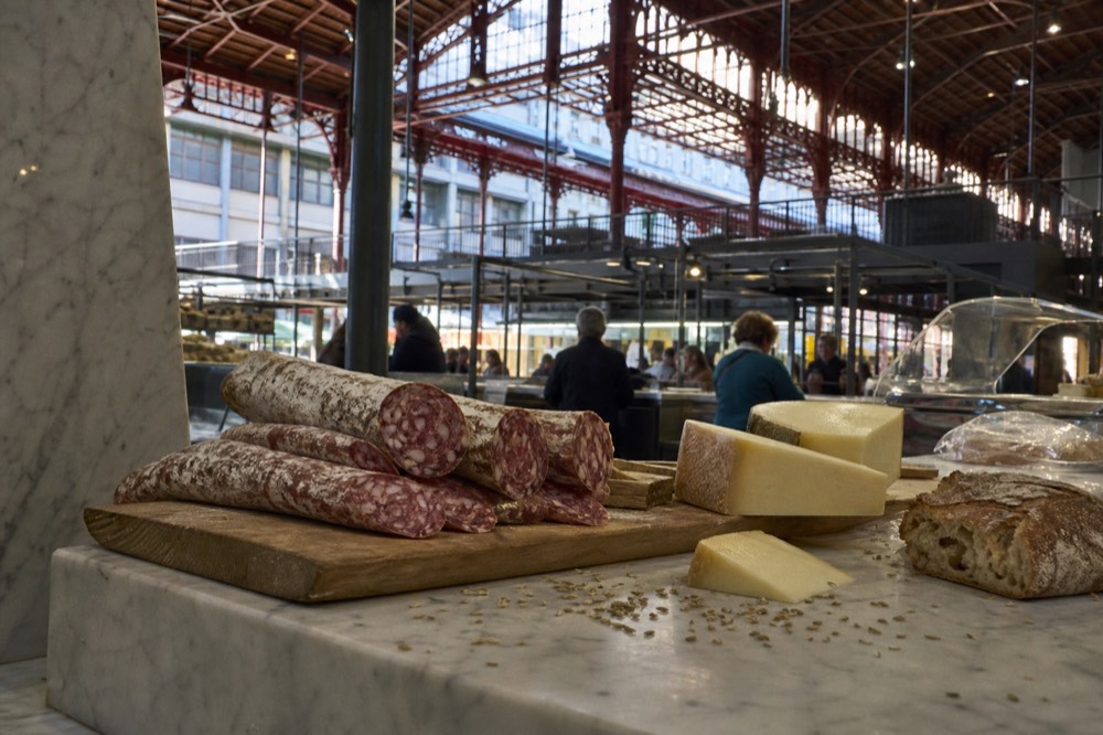 A deli counter with Tuscan salami, pecorino cheese and bread arranged on marble