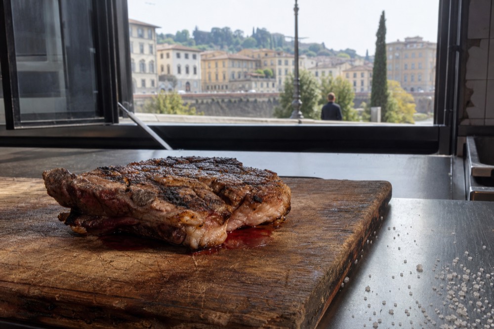A thick T-bone steak with grill marks resting on a butcher board