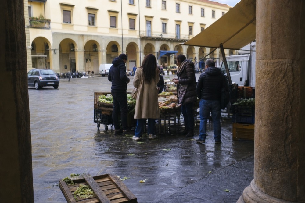 A small group standing at a market stall tasting cheese and cured meat with a guide