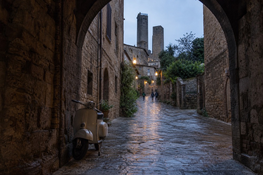 Narrow stone street in a Tuscan hill town with an arched gateway