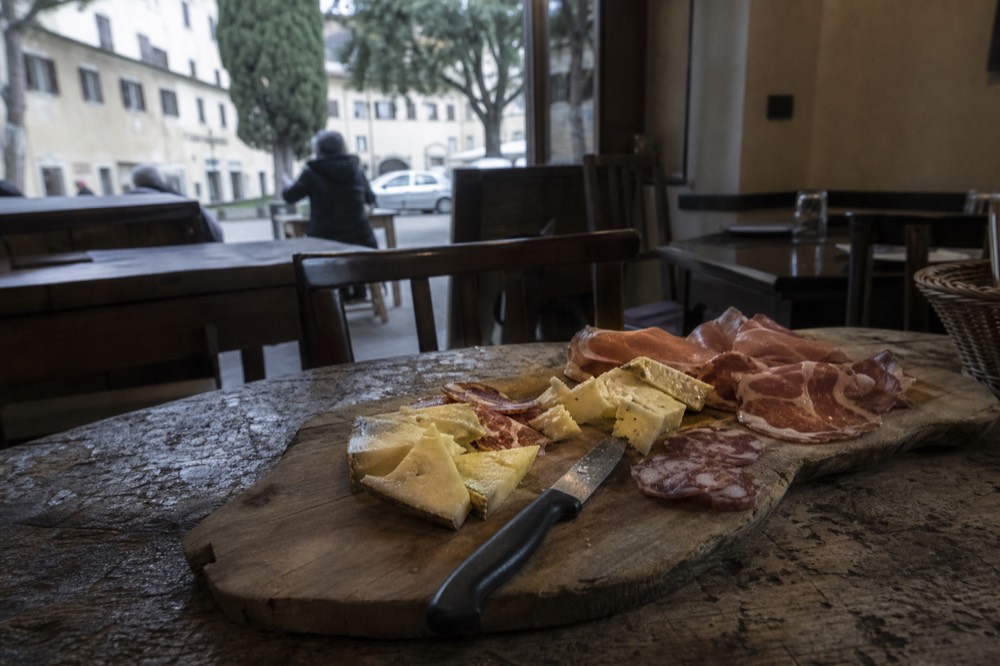 Assorted Tuscan cheeses and cured meats arranged on a wooden board