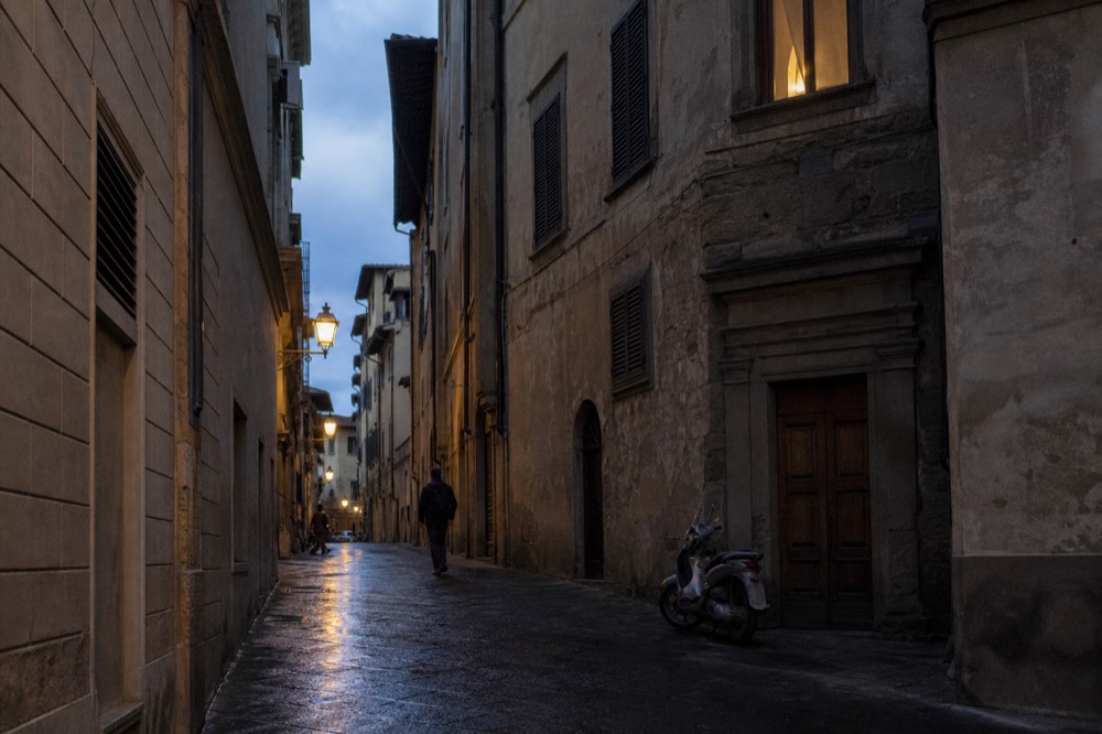 A narrow lane in central Florence with stone buildings and closed wooden shutters