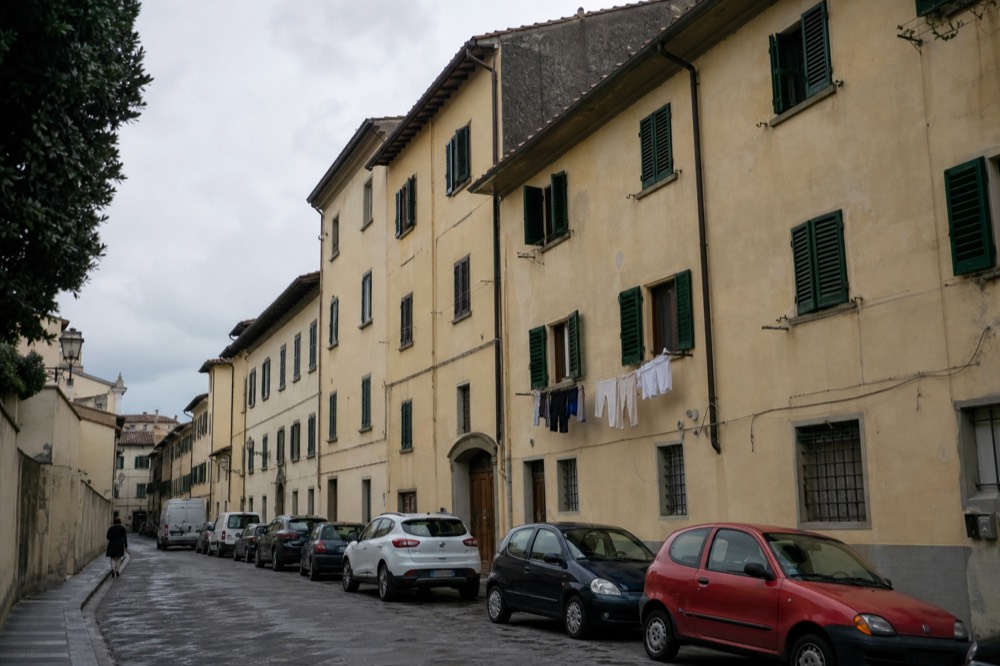 A row of Florentine apartment buildings with terracotta roofs seen from a side street