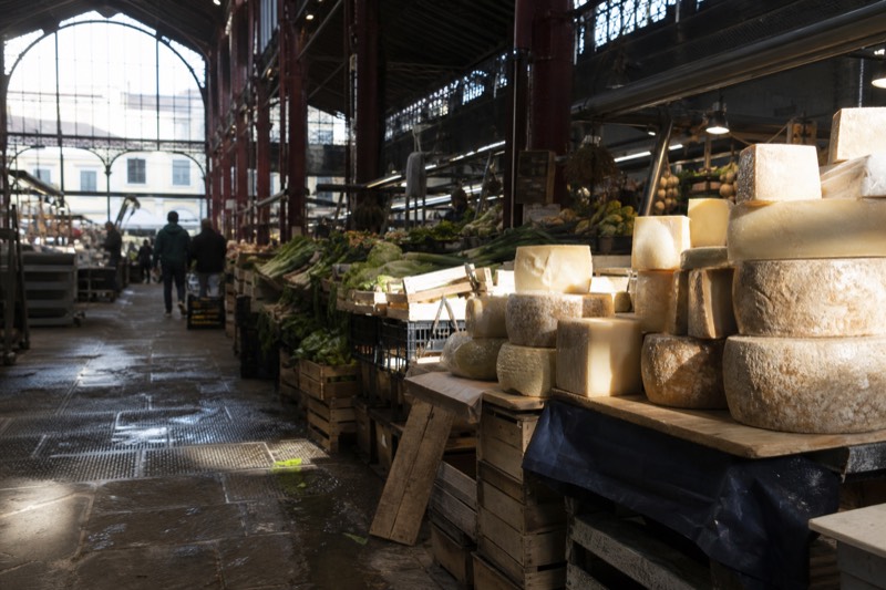 Produce and cheese stalls inside a covered food market in Florence, Italy.