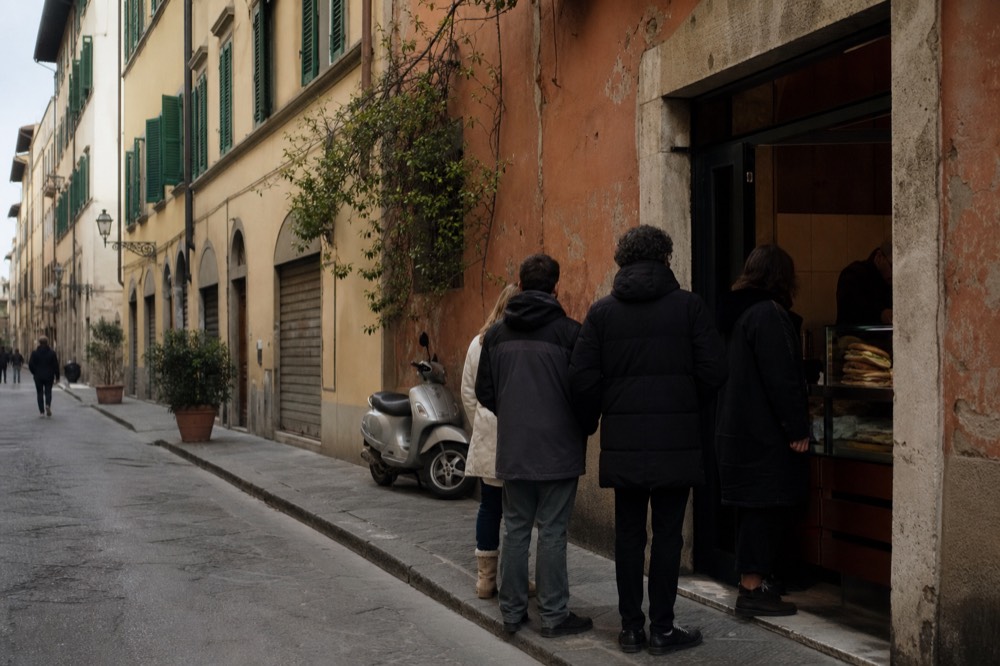 A Florence street corner with a sandwich shop counter and a short queue of customers