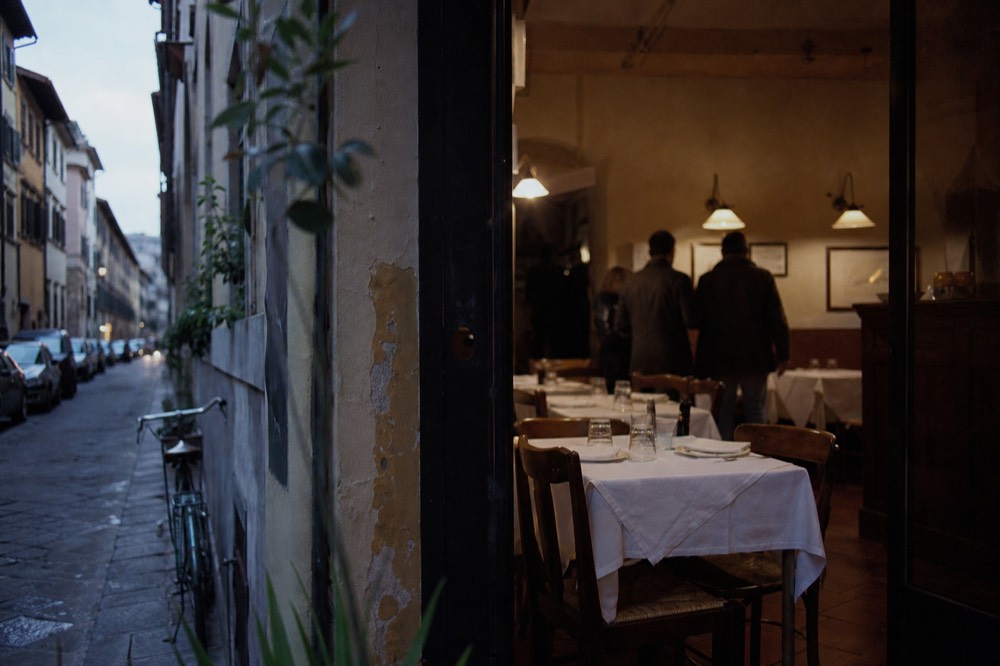 A small restaurant interior in Florence with wooden tables set for a few diners