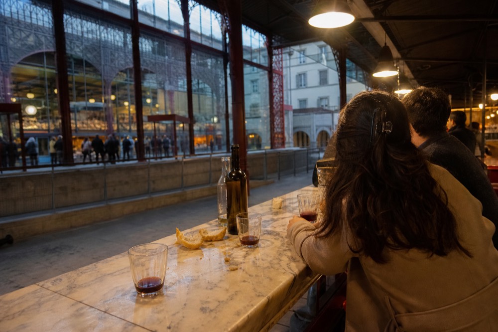 A small group tasting red wine at a market food hall counter