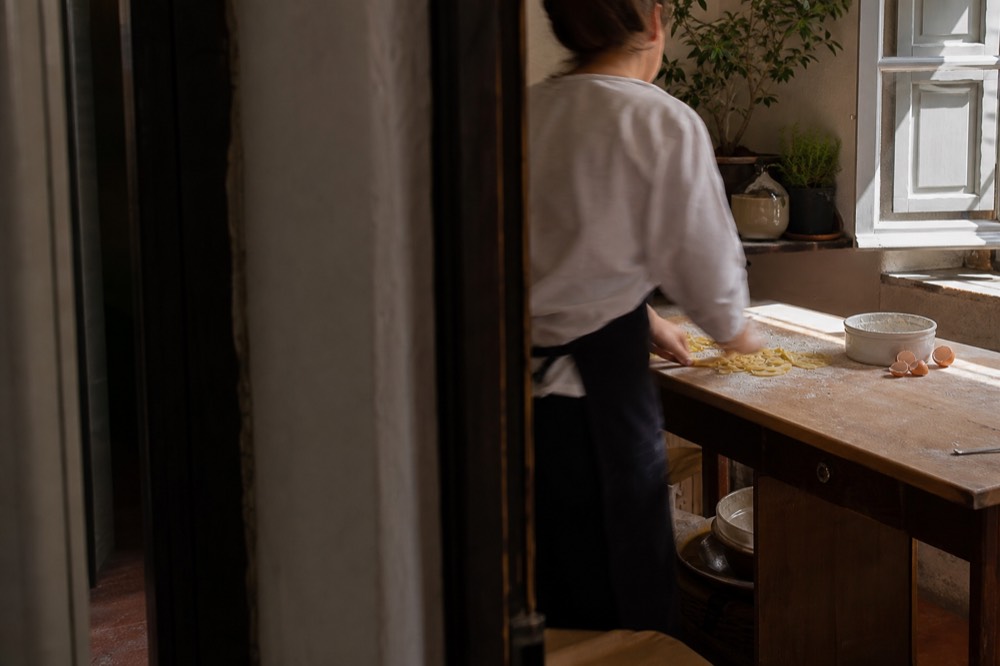 Hands preparing fresh pasta at a wooden counter during a cooking class