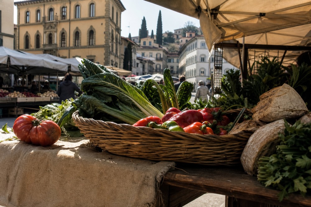 A basket of fresh vegetables and bread on a market stall table
