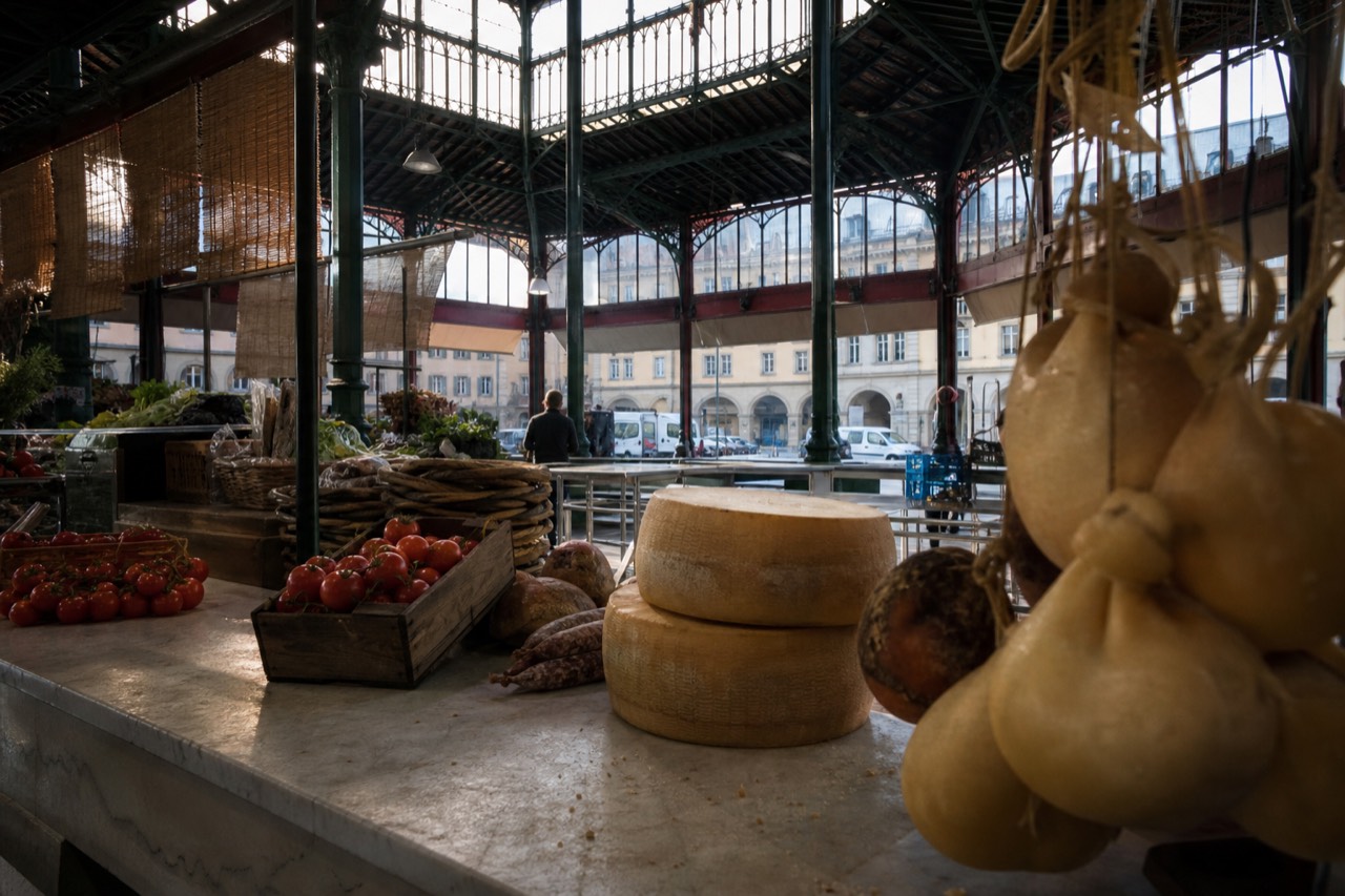 Market stalls with fresh produce and cured meats under an iron and glass roof in Florence
