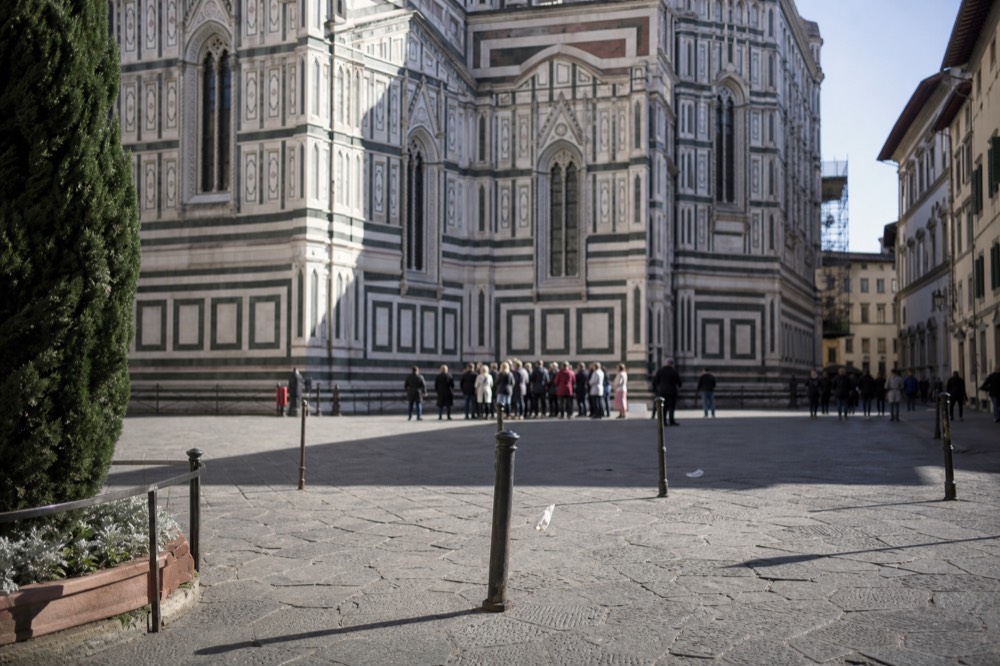 A guided group standing in a sunlit Florentine square