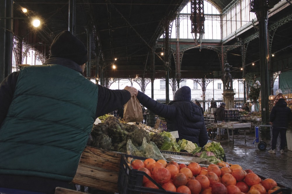 A covered market hall with produce stalls and hanging lights