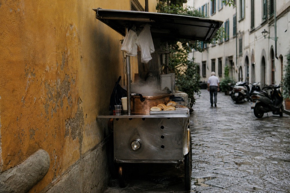 A street food cart in Florence with a copper pot and bread rolls on the counter