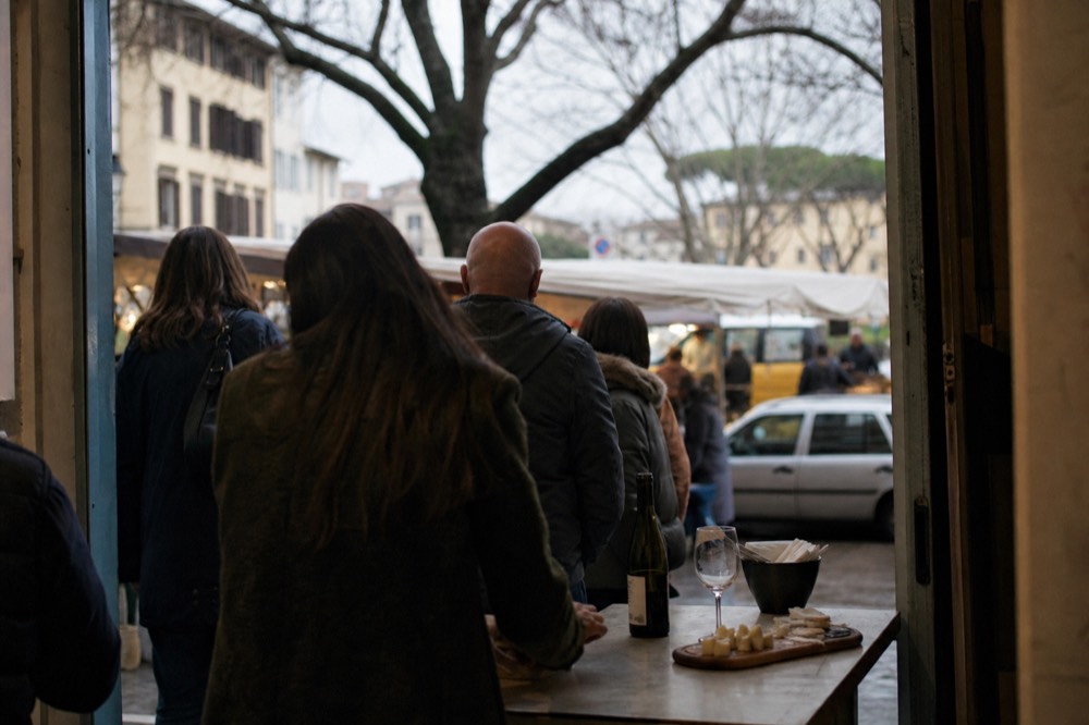A small group of visitors standing at a Florence food counter during a tasting stop