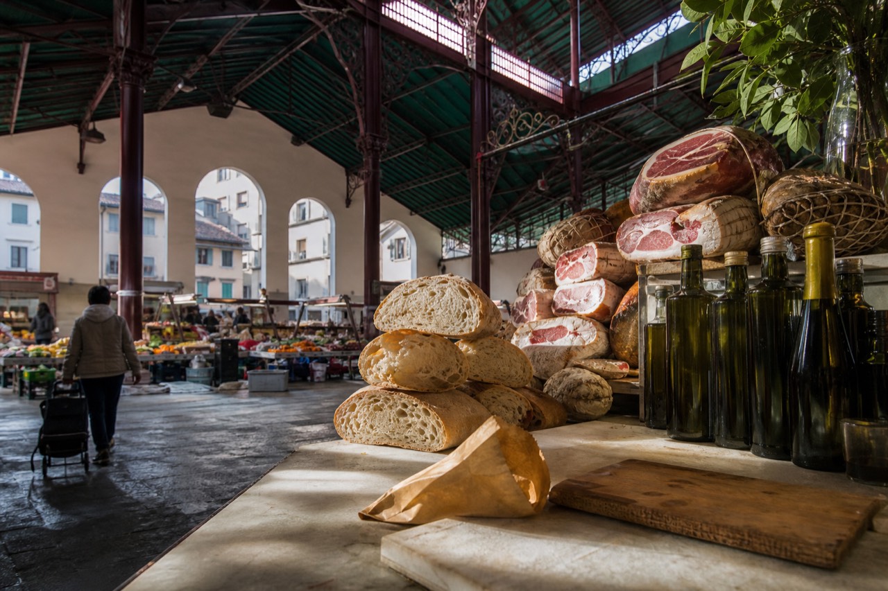 A Florence market counter with cured meats, bread and bottles of olive oil on display