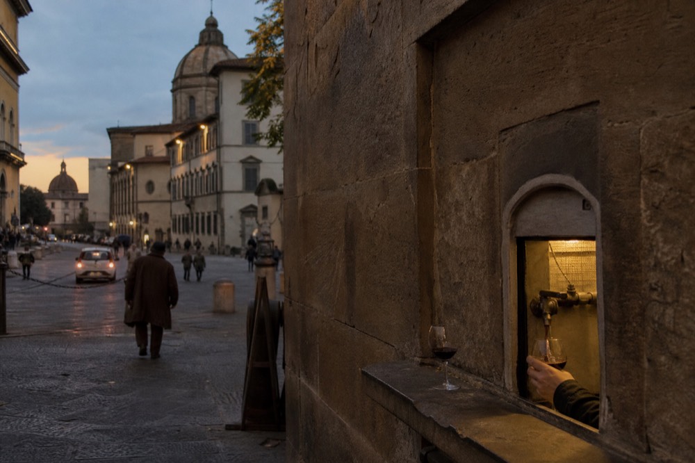 A wine window in a Florence street with a small glass being poured