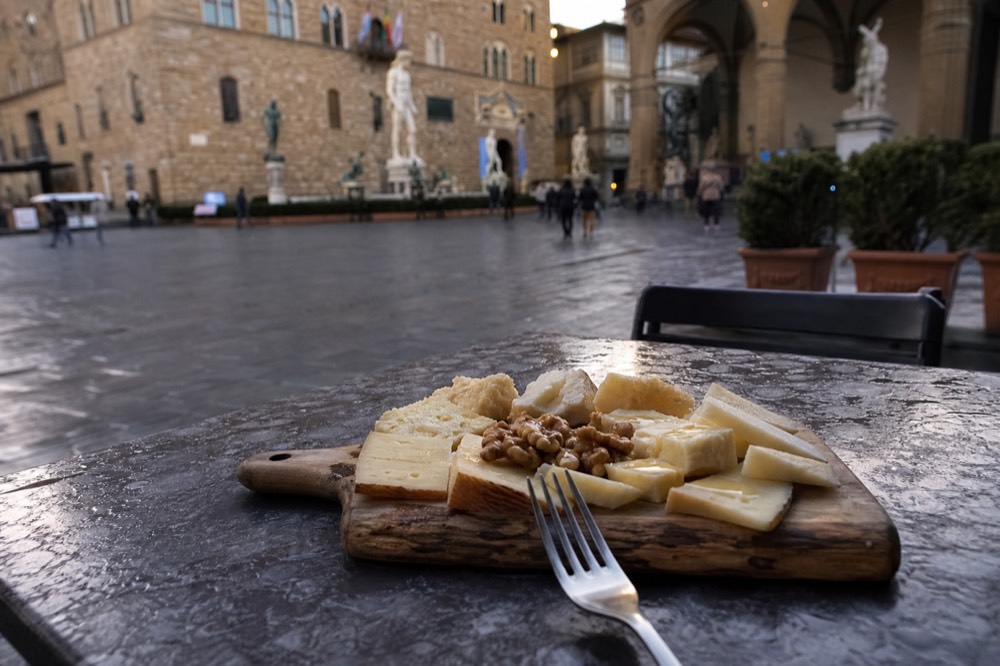 A plate of Tuscan cheeses with honey and walnuts on a wooden board
