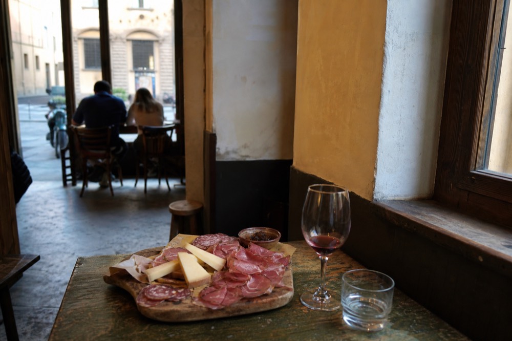 A plate of Tuscan cured meats and cheeses served on a wooden board in a Florence enoteca