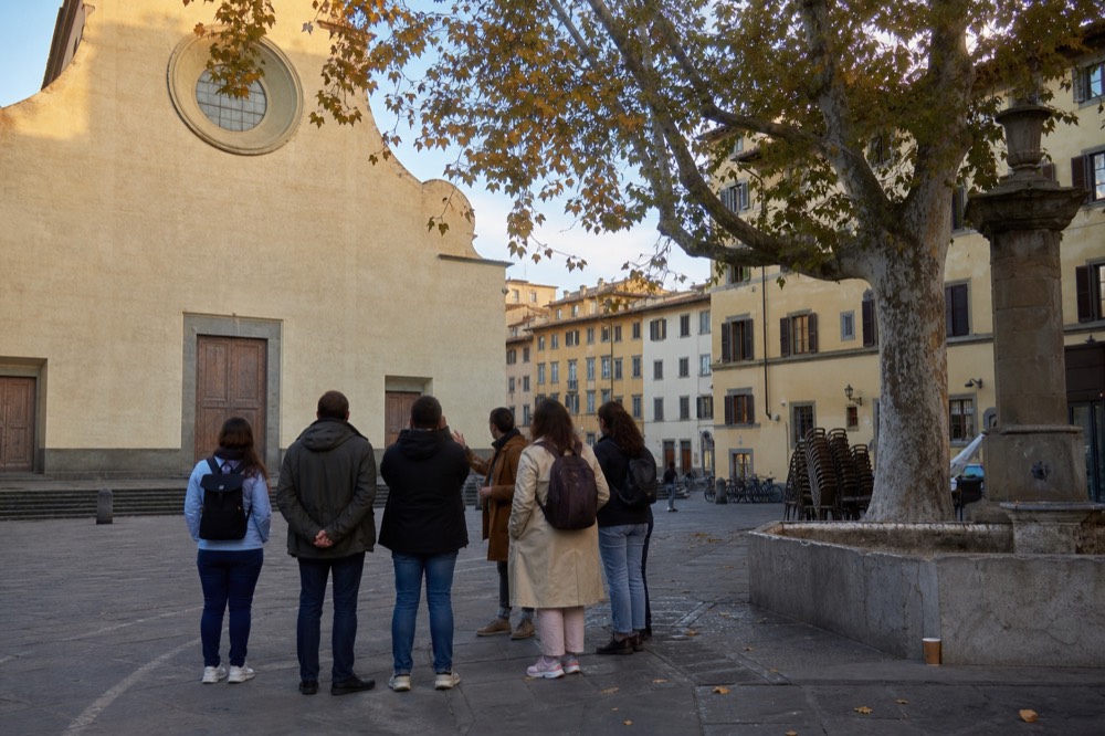 A Florence food tour guide speaking to a small group in a quiet piazza