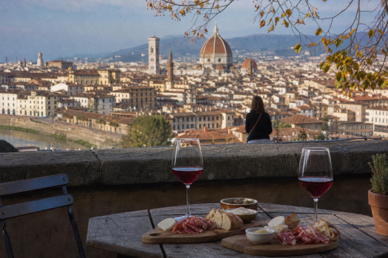 A table set with Tuscan antipasti, wine glasses and a view of Florence rooftops