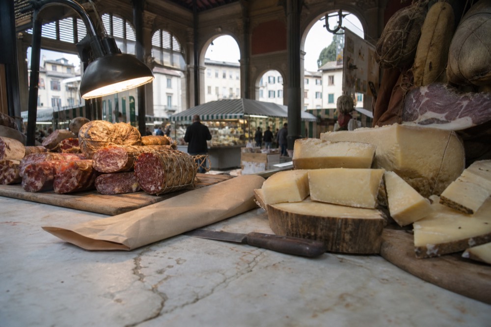Market hall interior with cured meats and cheese displayed on a marble counter