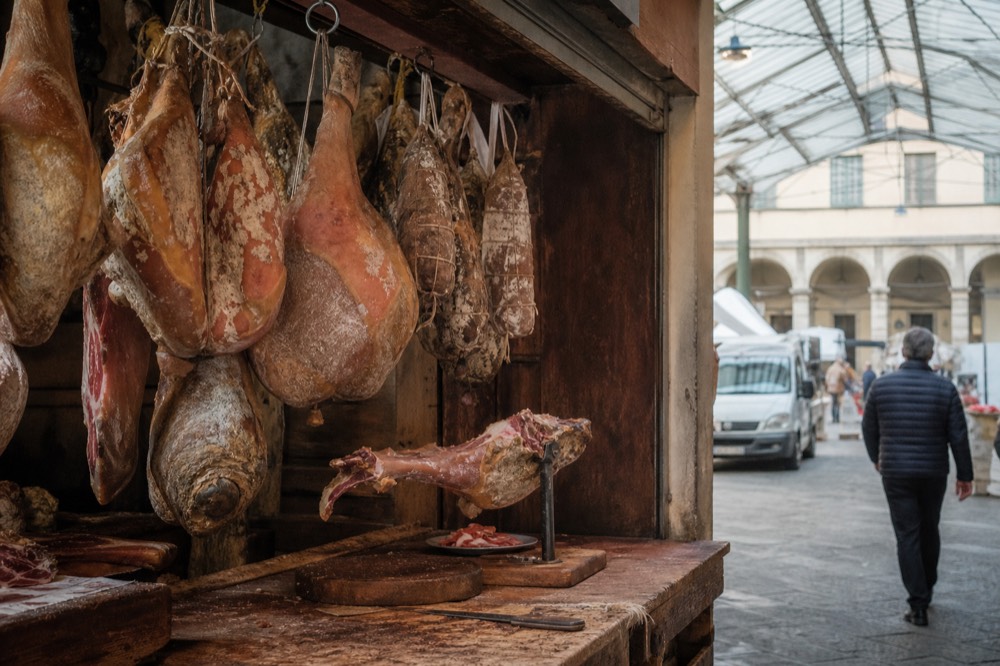 Butcher stall with hanging Tuscan meats and a wooden counter in a market hall