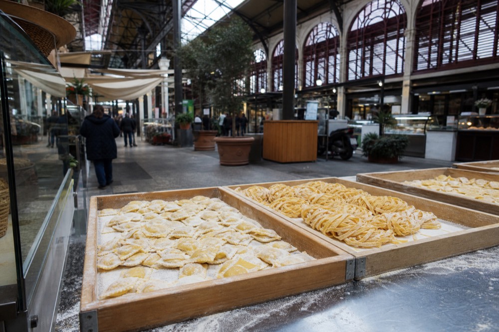 Fresh pasta displayed in trays at an artisan food stall counter