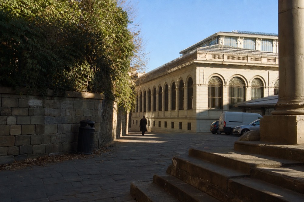 Exterior of a nineteenth century market building with stone arches and a glass roof