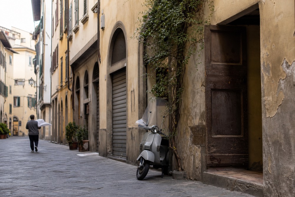 Old workshops and shuttered storefronts on a narrow Oltrarno street