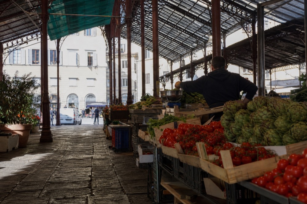 Market stalls with produce under a restored glass canopy
