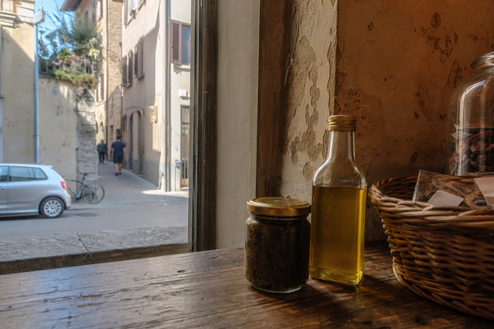 A glass jar of truffle preserves and a bottle of truffle oil on a wooden shop counter