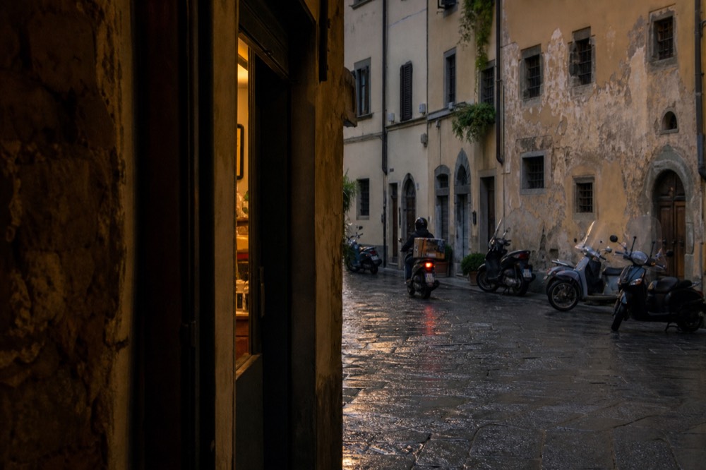 A narrow Florentine street with restricted traffic signs and parked scooters